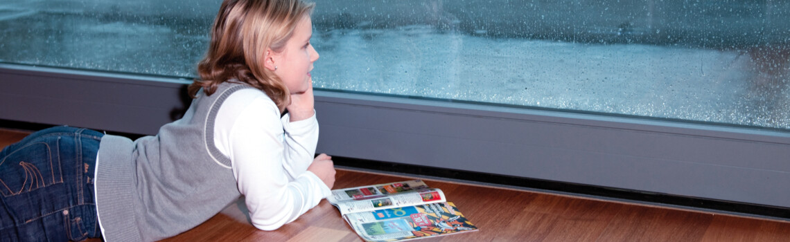 Kind schaut aus der Terrassentür und sieht das auf der Terrasse alles durch den Regen nass wird. | © Gutjahr Systemtechnik