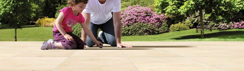 Vater mit Mädchen sitzen auf deinem Terrassenbelag im Untergrund eine Drainage | © Gutjahr Systemtechnik