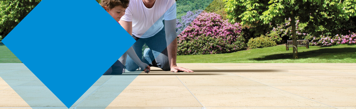 Vater mit Mädchen sitzen auf deinem Terrassenbelag im Untergrund eine Drainage | © Gutjahr Systemtechnik