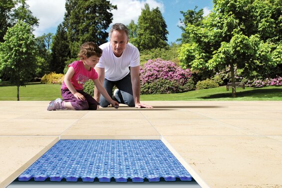 Schütze deinen Terrassenbelag | © Gutjahr Systemtechnik Vater mit Mädchen sitzen auf deinem Terrassenbelag im Untergrund eine Drainage | © Gutjahr Systemtechnik