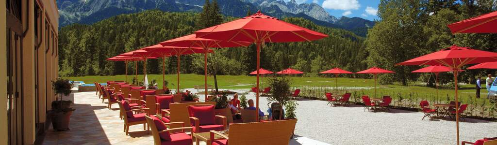 Titelbild Gutjahr Terrasse Terrasse mit roten Schirmen und einer Berglandschaft im Hintergrund