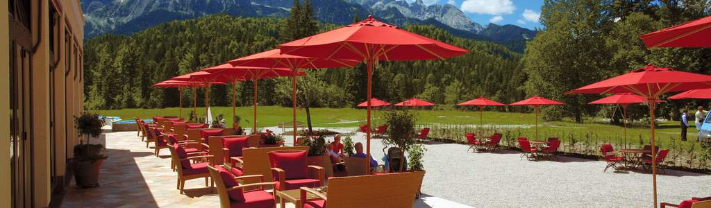 Terrasse mit roten Schirmen und einer Berglandschaft im Hintergrund