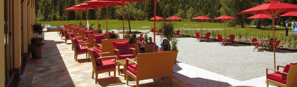 Terrasse mit roten Schirmen und einer Berglandschaft im Hintergrund