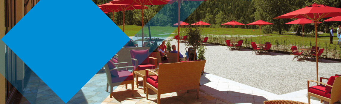 Terrasse mit roten Schirmen und einer Berglandschaft im Hintergrund
