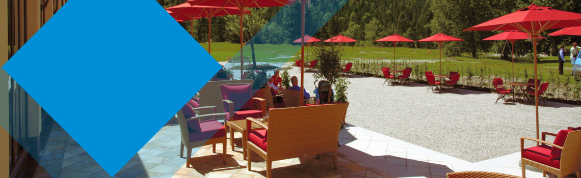 Terrasse mit roten Schirmen und einer Berglandschaft im Hintergrund