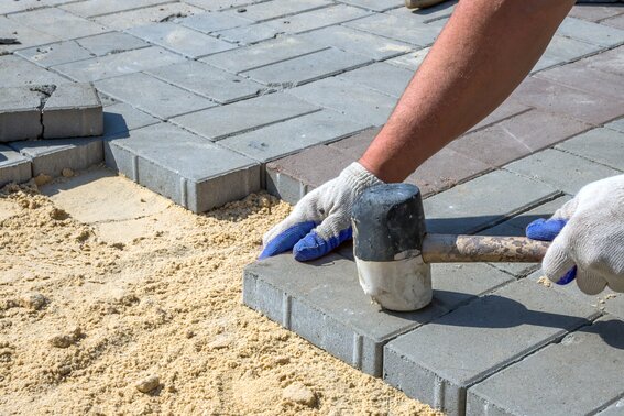 Handwerker der ein Betonwerkstein fest klopft